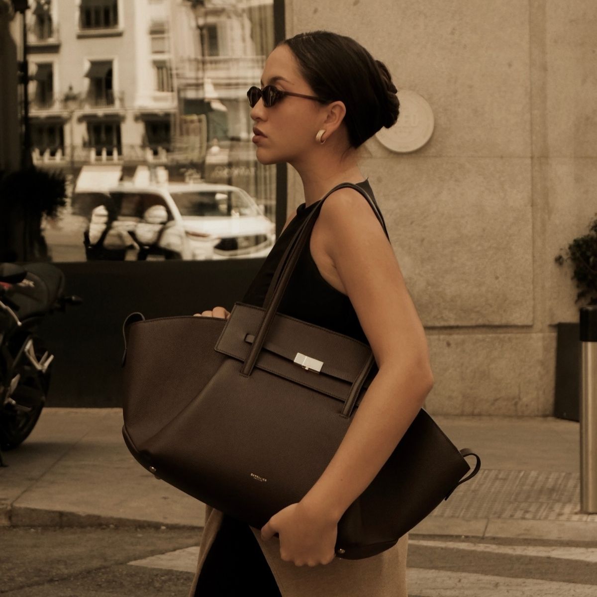 Woman wears leather jacket, carries DeMellier Brooklyn bag