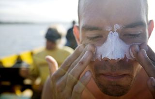 A man applies zinc sunscreen to his face.