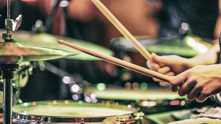 Side profile of a person playing a drum kit