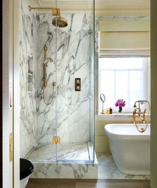 marble and brass bathroom with shower enclosure and freestanding bath