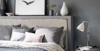 grey bedroom with close up detail of an upholstered headboard with items on top