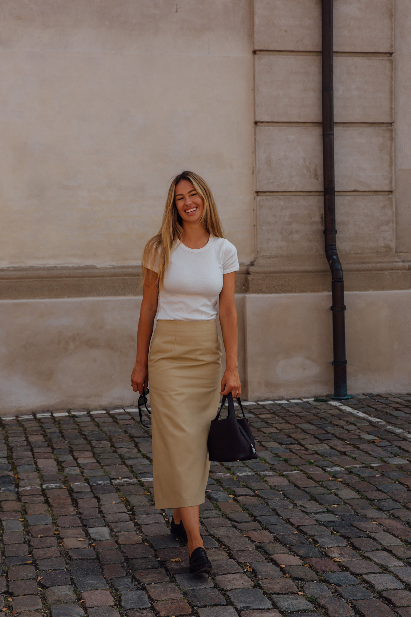 Fashion week attendee wearing a white tshirt, beige pencil skirt, and black shoes