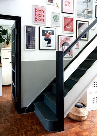 Dark black wood staircase with black framed photos on the wall