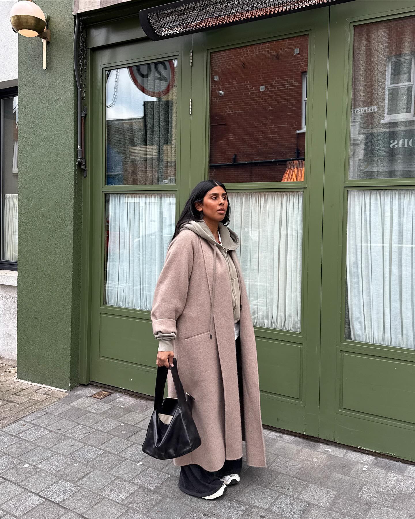 Monikh in a wool coat carrying a leather tote