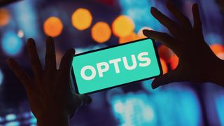 Optus logo is displayed on smartphone, lights are in the background