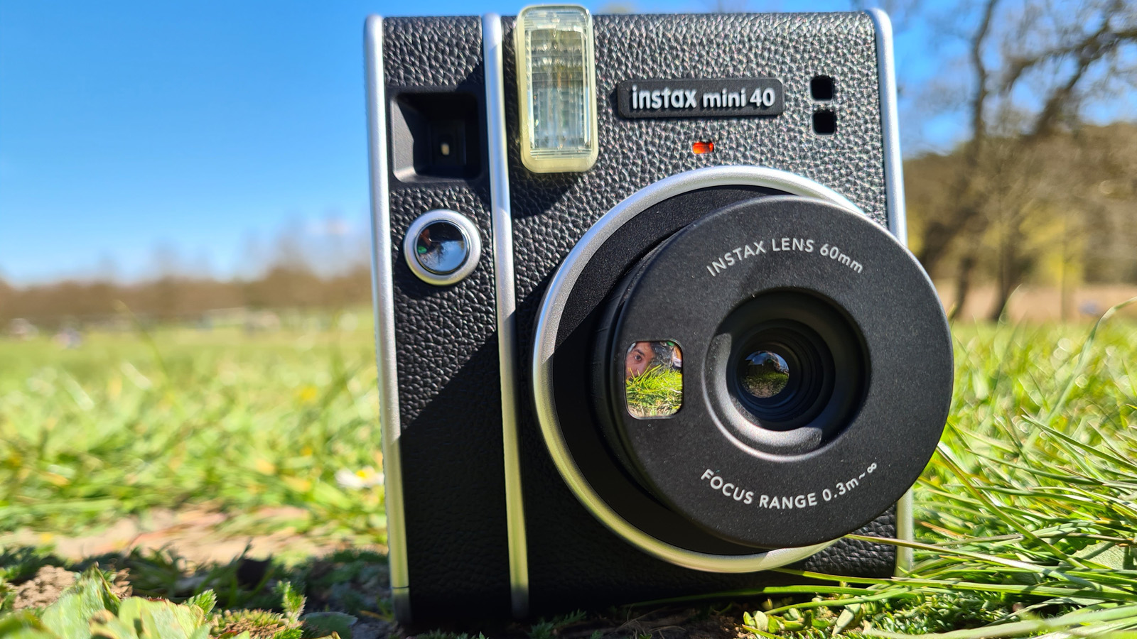A Fujifilm Instax Mini 40 instant camera sat on a grass lawn