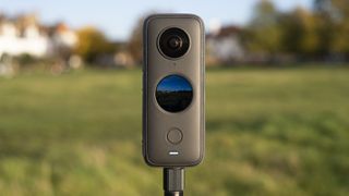 Insta360 One X2 mounted on tripod with a field in the background