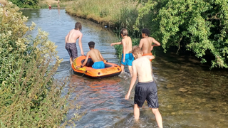 Image of children enjoying National Play Day in a stream with a raft