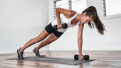 A woman performing a renegade row with dumbbells