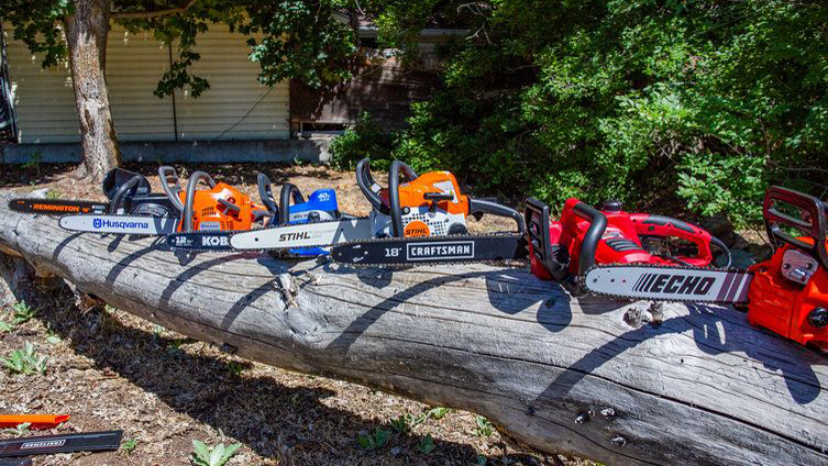 Best chainsaws: An image of several chainsaws lined up on a fallen tree trunk