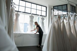 Bridal boutique owner arranging wedding dress window display