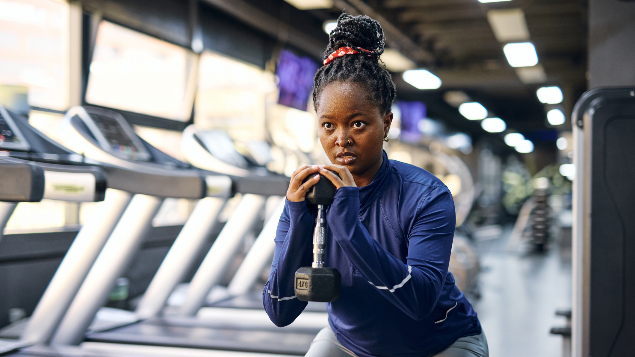 Woman exercising with dumbbell in front of a line of treadmills