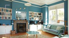 Blue living room with tidy decluttered bookshelves either side of a fireplace to show how to declutter books 