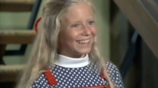 Eve Plumb as Jan Brady, smiling and wearing a turtleneck