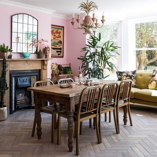 living room with pink wall woodden floor table and chairs