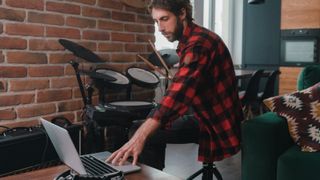 Man with a laptop on an electronic drum kit 