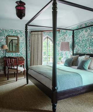 bedroom with wooden four poster and patterned wallpaper