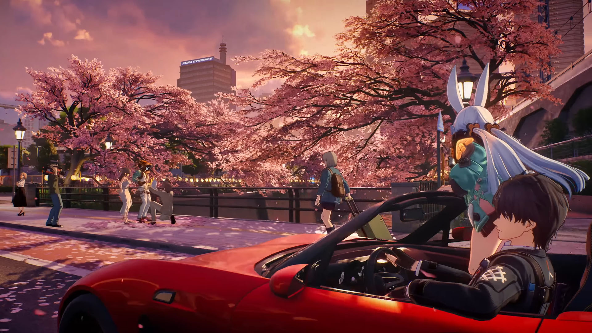 Two characters cruise through Nova City in. an open top sports car in Ananta, from the PlayStation gameplay trailer, looking at sakura in bloom