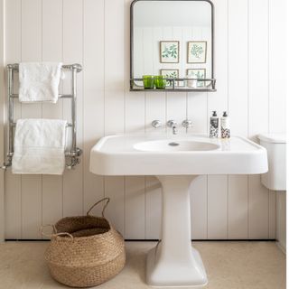 bathroom with white basin, silver towel rail and beige storage basket