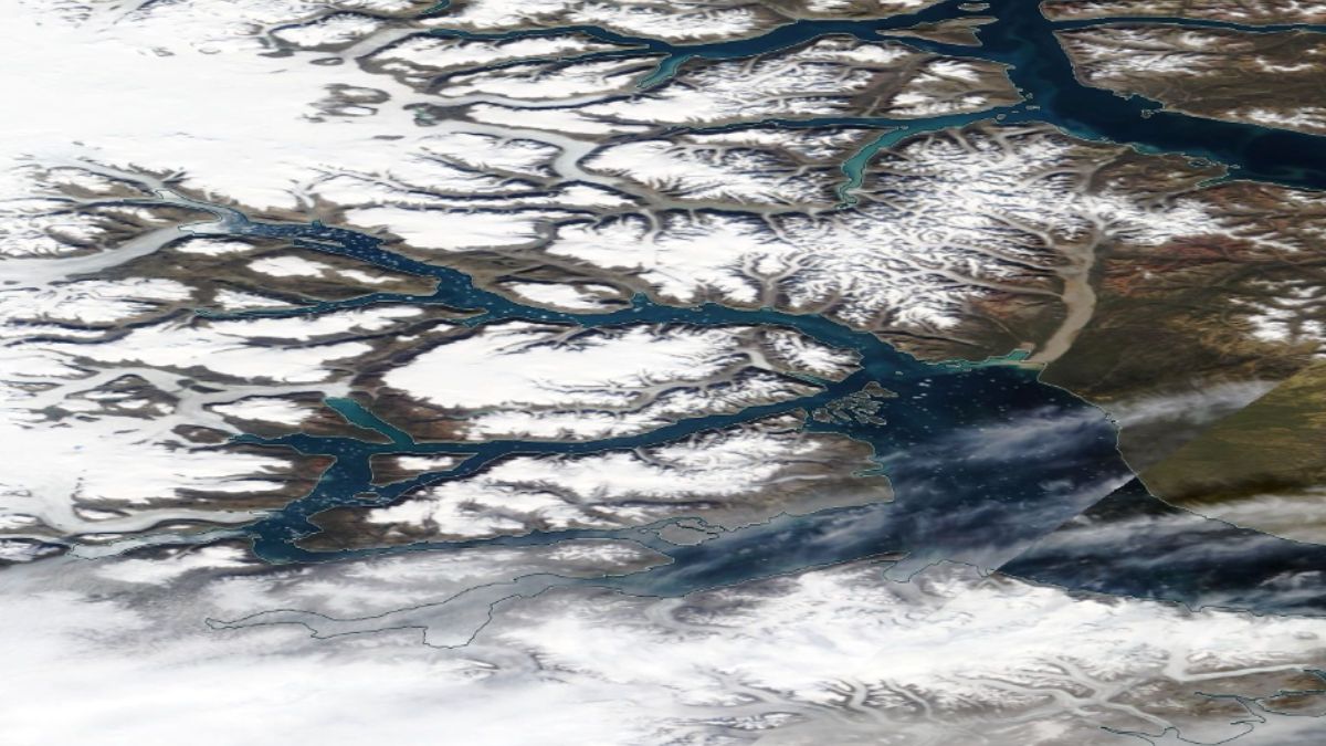 satellite view of scoresby sund, greenland. showing snowcapped land and deep blue water.