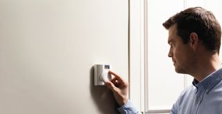 man turning down thermostat on wall