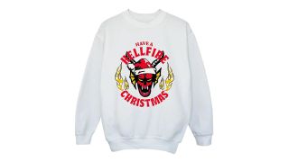 best Christmas Jumpers illustrated by a white sweatshirt featuring a Stranger Things logo with a santa hat