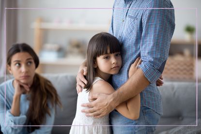 Sad girl hugging dad while mum watches looking unhappy