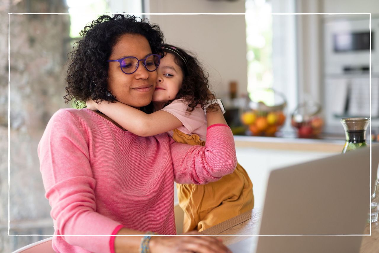 Mother and daughter hugging while looking at laptop at home