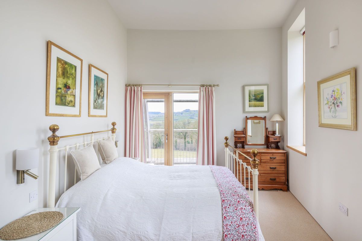 The bedroom has bifold doors leading onto a balcony and a small nightstand