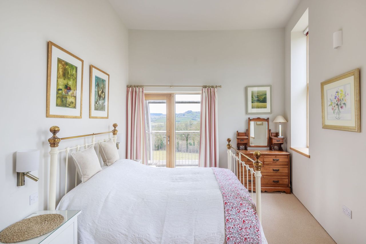 The bedroom has bifold doors leading onto a balcony and a small nightstand