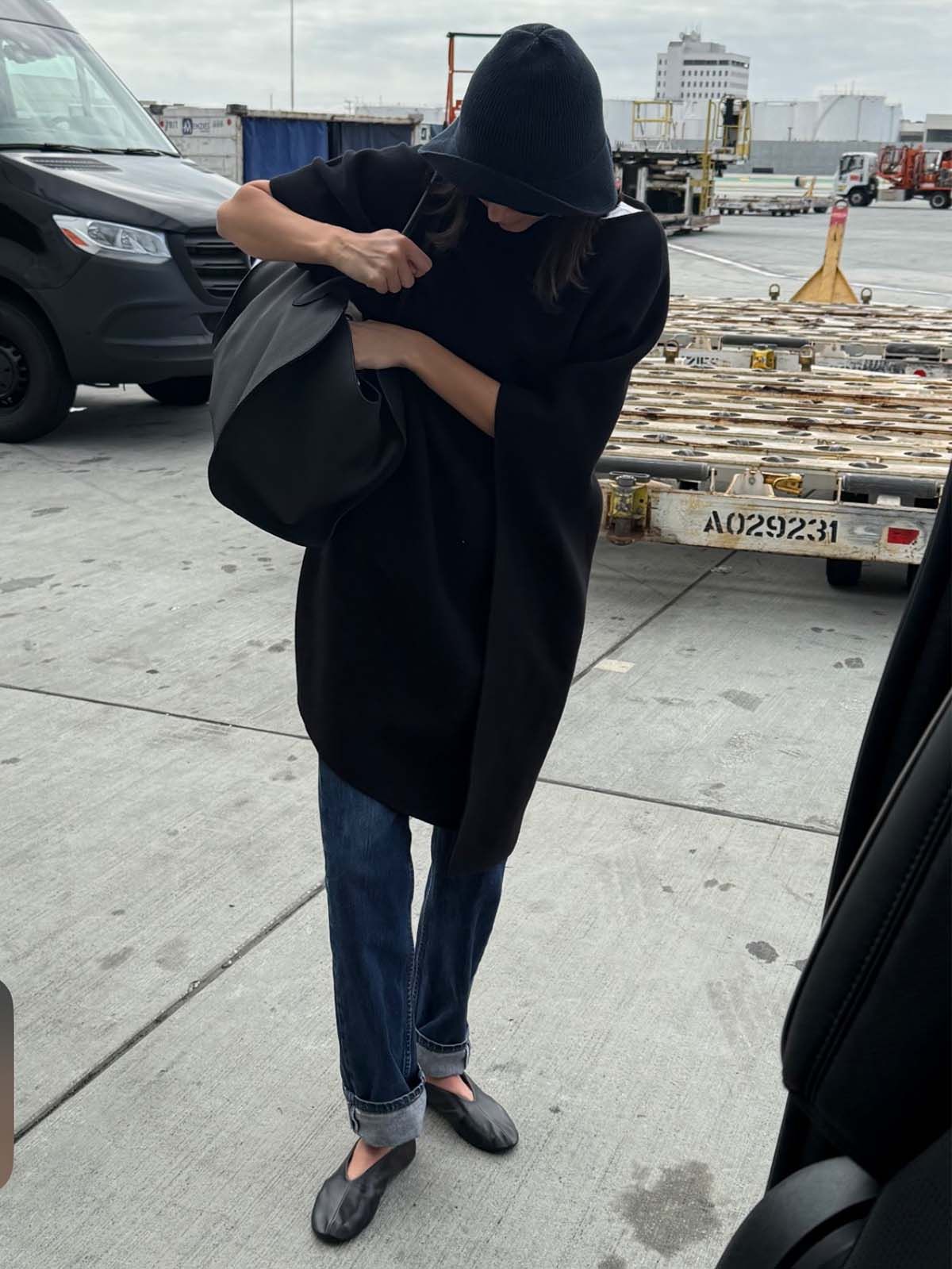 Kendall Jenner wearing a cape coat, The Row Marlo bag, The Row hat, The Row glove flats, and cuffed, dark-wash jeans.