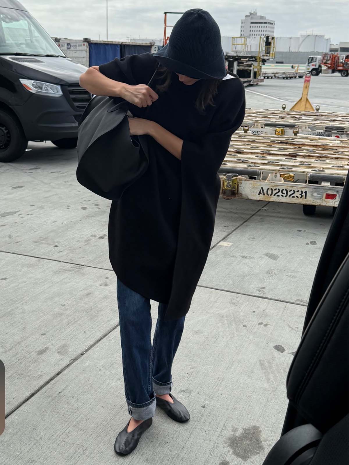 Kendall Jenner wearing a cape coat, The Row Marlo bag, The Row hat, The Row glove flats, and cuffed, dark-wash jeans.