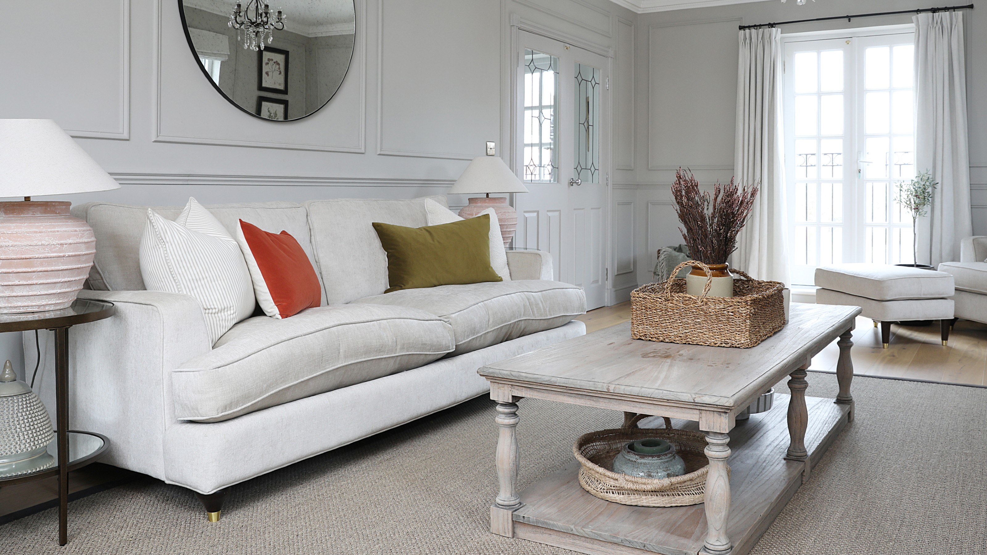 A grey living room with wall panelling, a grey rug and a cream sofa