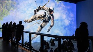 An astronaut hovers over a space station in an immersive projection-mapping spectacle. 