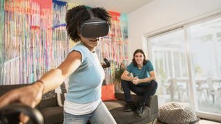 oculus quest gamer wearing headset and controller, with friend on sofa