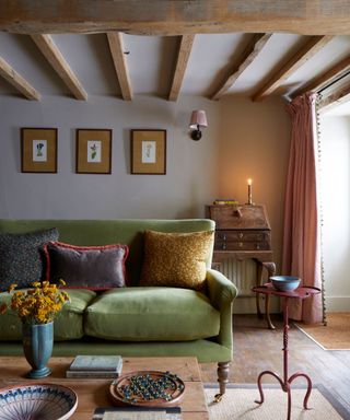 Cottage sitting room with ceiling beams and a green sofa