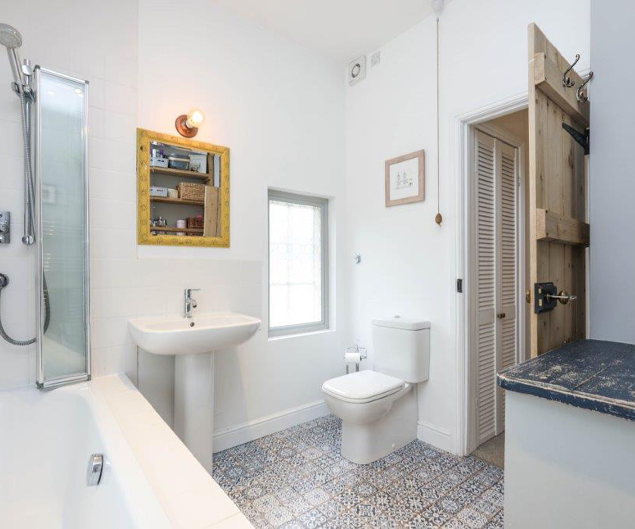 white bathroom with blue patterned floor tiles and yellow bathroom mirror