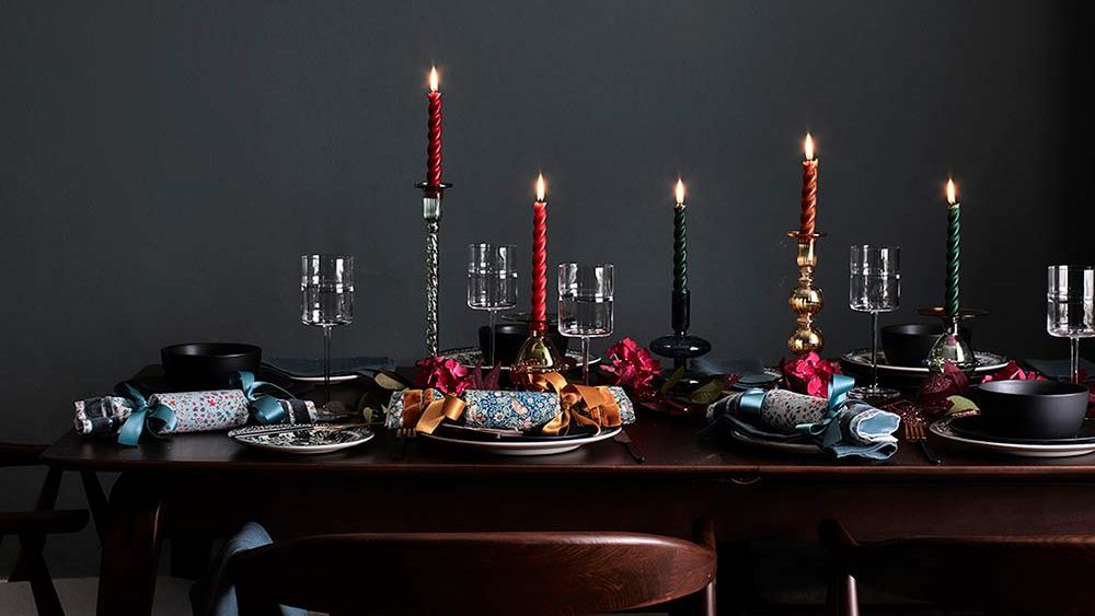 Green dining room with table decorated for Christmas with crackers and red and green candles