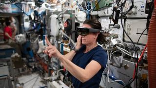 a woman in space wears a vr headset while holding up a finger in the air
