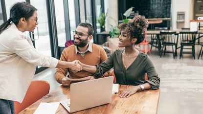 A financial adviser shakes hands with clients in an office.