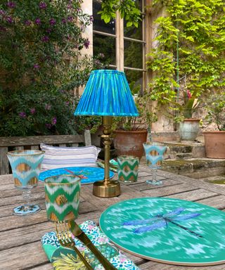 Color pop blue portable table lamp, with patterned glassware, dragonfly design placemat, and patterned place setting.