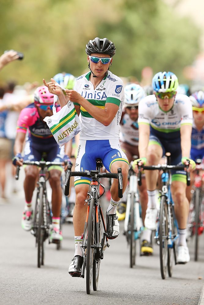 Patrick Lane of team UniSa-Australia pics up supplies at the front of the peloton as he goes through the hydration station