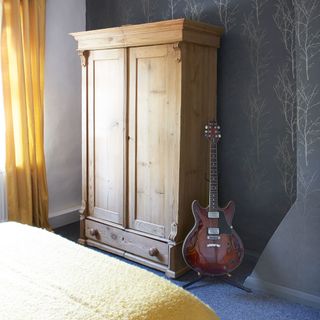 room with wall paper on wall and wooden couboard