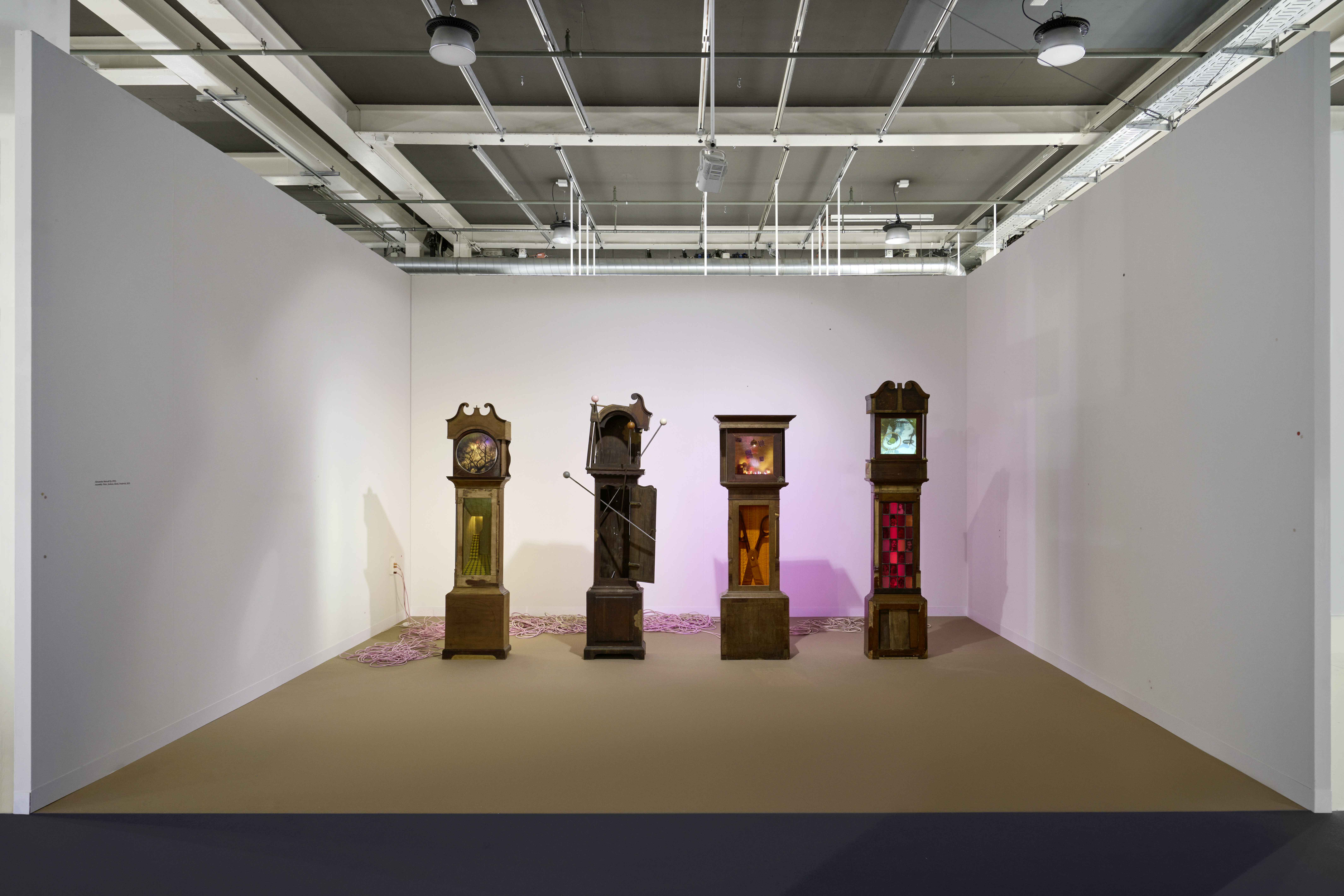 Installation views of a series of grandfather clocks displayed in an art gallery.