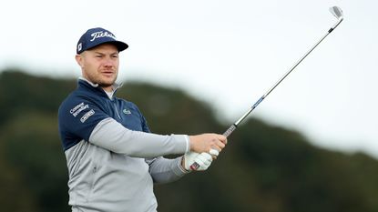 Oliver Fisher holds his finish on an iron shot