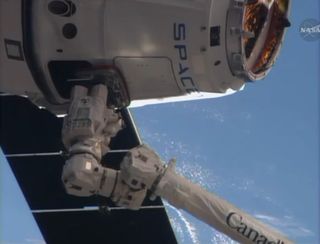 A SpaceX Dragon cargo ship is captured by astronauts using the robotic arm on the International Space Station in this close-up camera view from the outpost on April 20, 2014. The Dragon capsule delivered nearly 5,000 lbs. of supplies to the space station