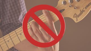 Close-up of fretting hand playing F barre chord with banned sign overlayed