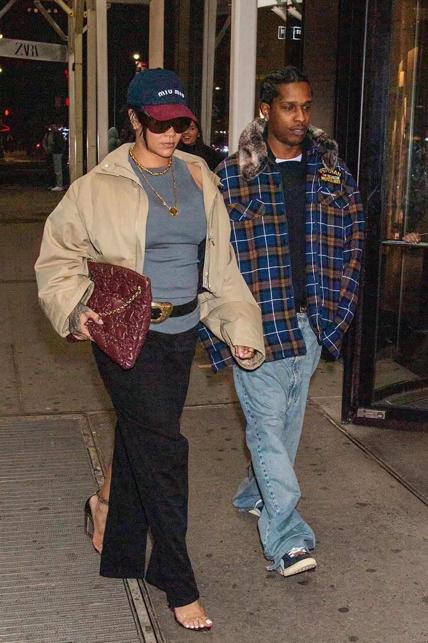 Rihanna wearing a two-toned Miu Miu baseball cap, gray tank top, black belt, black pants, burgundy Dior bag