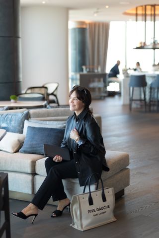 A former Nordstrom buyer wearing a faux leather button down with straight-leg black trousers and open-toe mules.