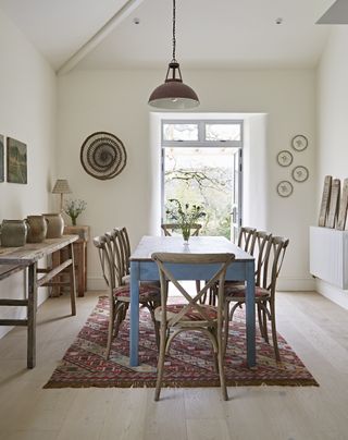 Neutral dining room with wooden dining table and chairs and a patterned nomad rug from Weaver Green